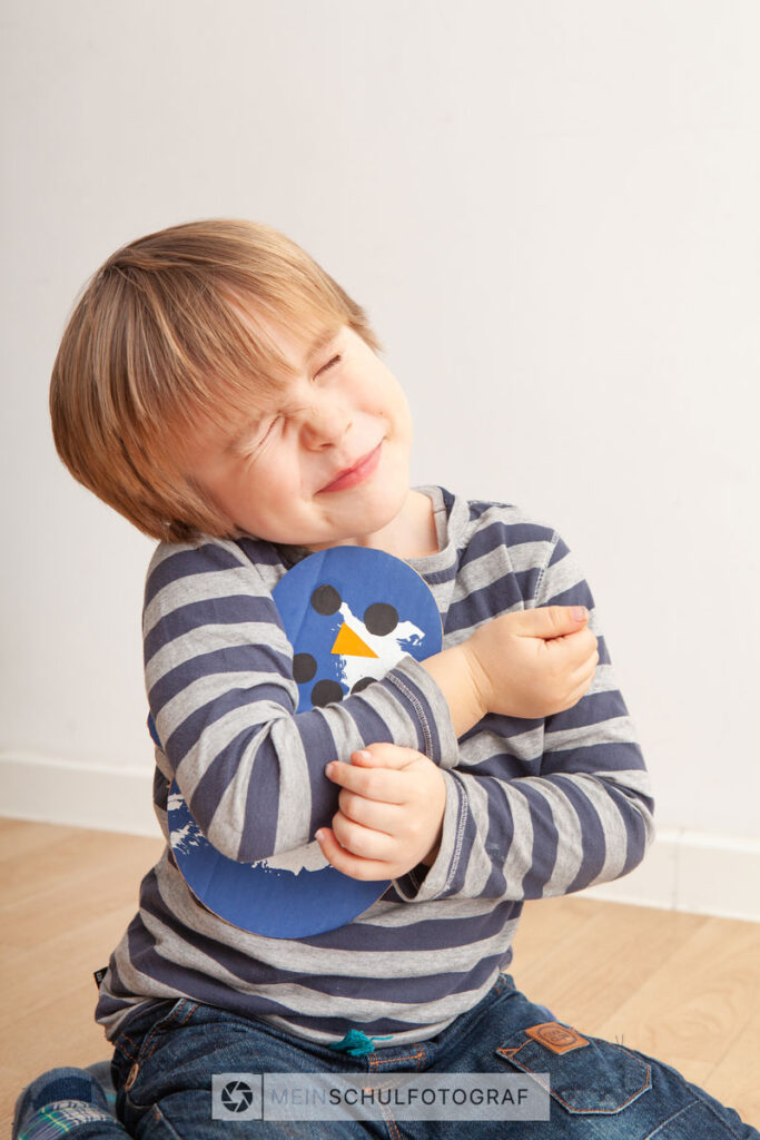 Schulfotografie von einem Kind welches ein Spielzeug umarmt